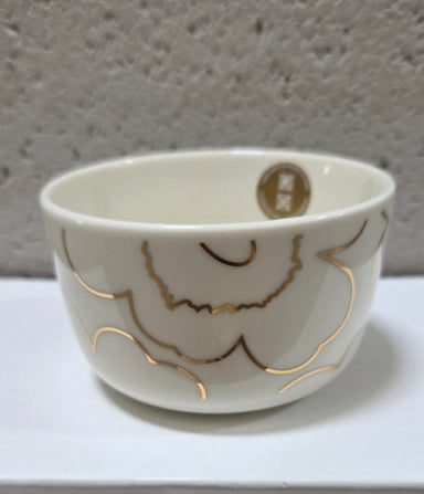 White ceramic cup with gold accents on a white background